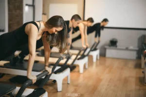 Bright Pilates reformer studio in New York City with diverse group of beginners exercising together