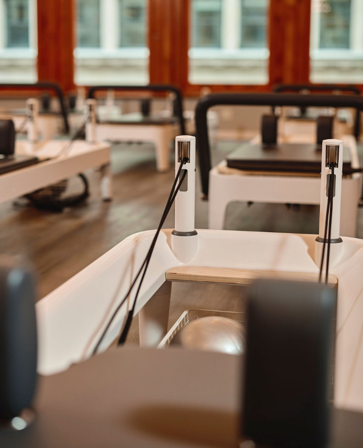 Close-up view of a studio-grade Pilates reformer showing carriage, springs, and footbar details