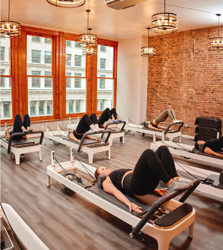 Group of participants training on Pilates reformers with instructor guidance