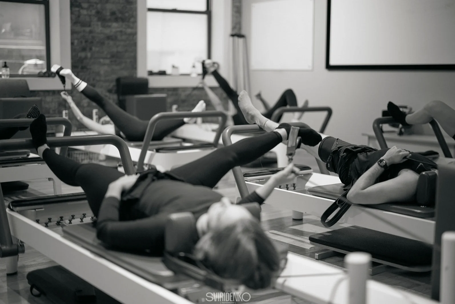 Participants practicing on reformer machines in a group Pilates class at BK Pilates NoMad studio