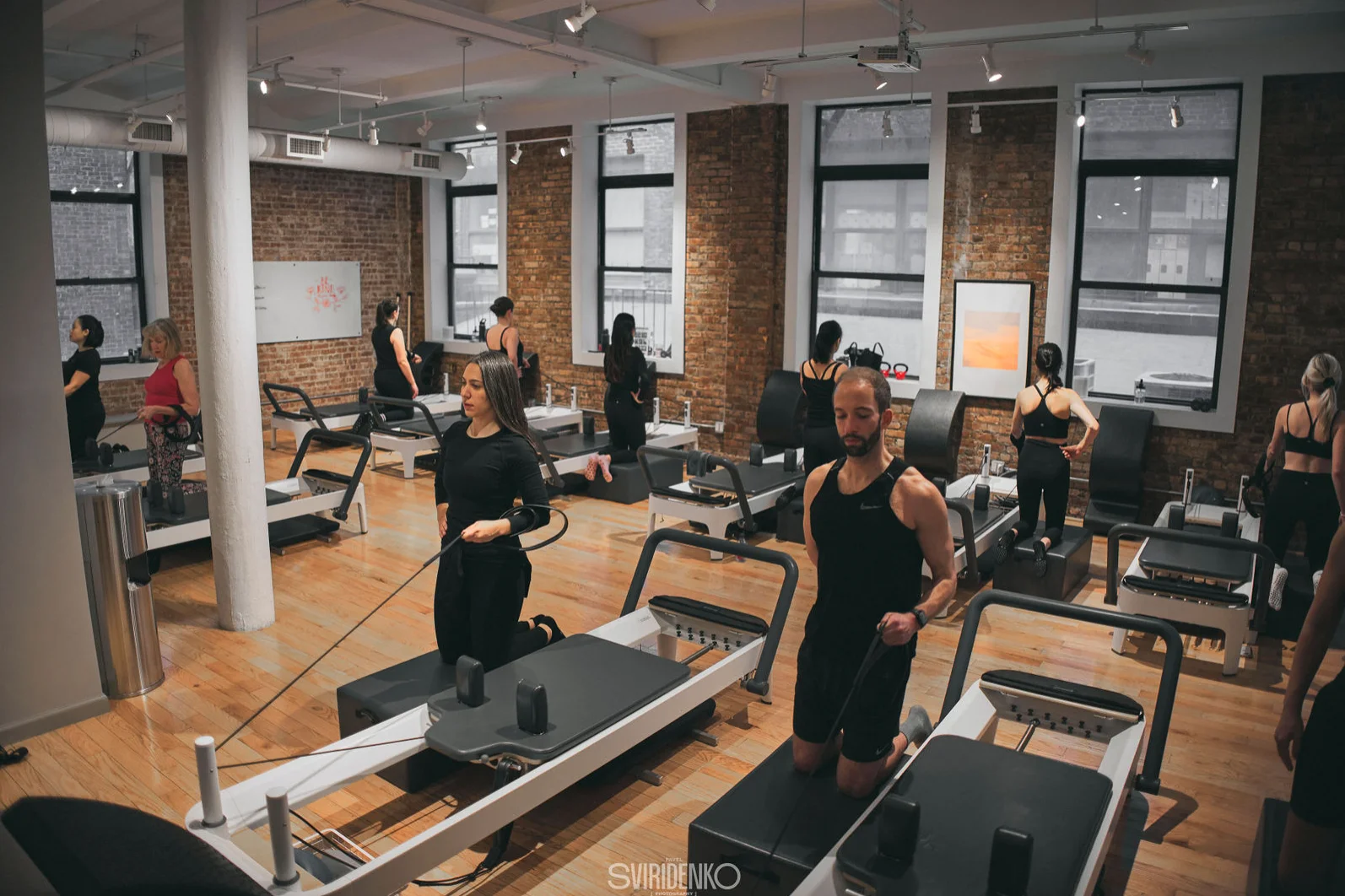 Pilates instructor assisting a client on a reformer machine during an exercise at BK Pilates NoMad studio