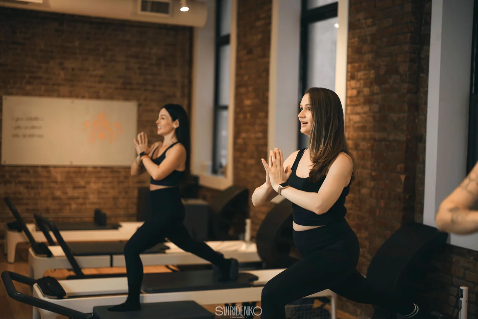 Instructor adjusting a client's form on a reformer machine during a Pilates session at BK Pilates NoMad