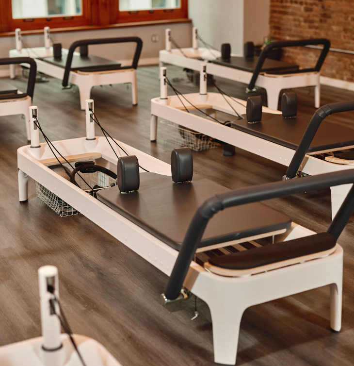Woman exercising on a Pilates reformer machine in a modern professional studio
