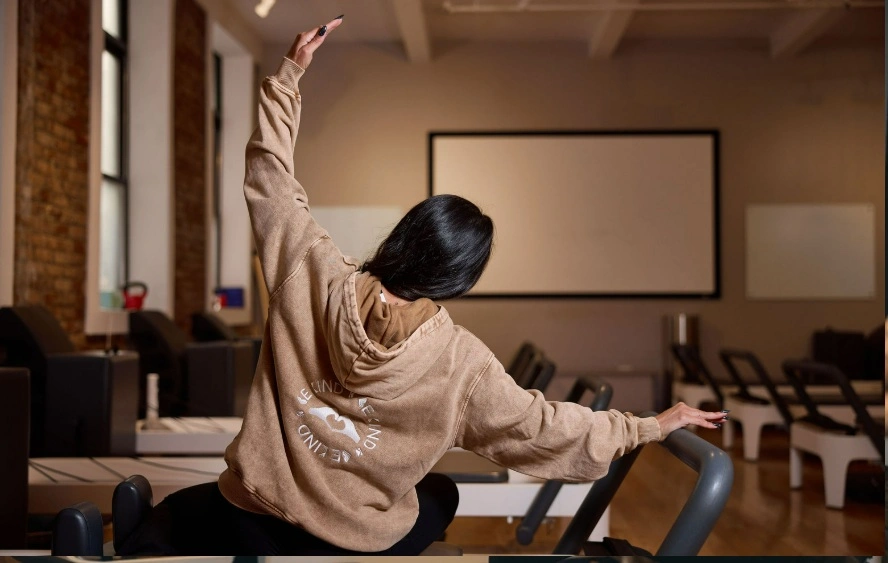 Woman stretching on a Pilates reformer at BK Pilates Studio Nomad, finding balance and calm during class.