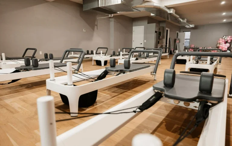 Row of professional white Pilates reformers in a spacious, sunlit studio