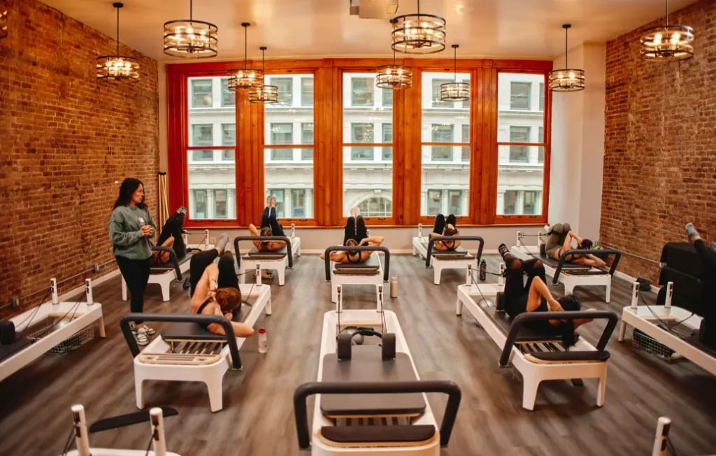 Group Pilates class with several individuals exercising on reformers