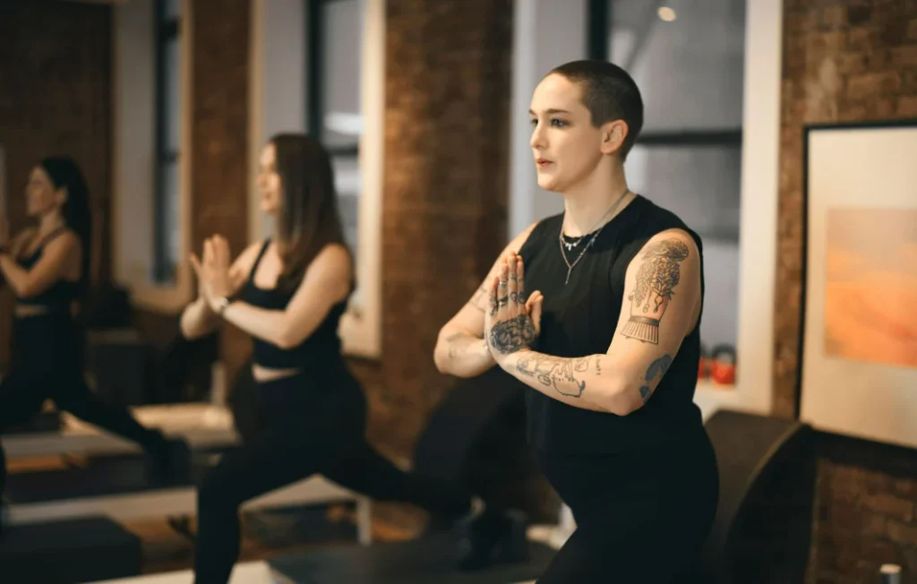 Close-up of a person with tattoos focused on a core-strengthening Pilates exercise in a professional studio setting.