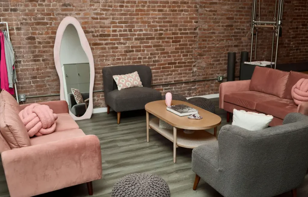 The relaxing lounge area at BK Pilates featuring velvet chairs and a brick wall, designed for a calming nervous system reset