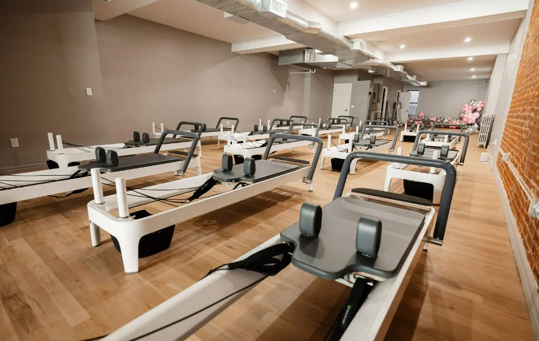 An empty Pilates studio with multiple reformers, ready for a class
