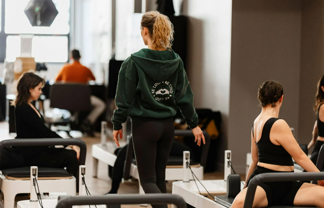 A person in a Pilates class performing a standing leg workout on a reformer