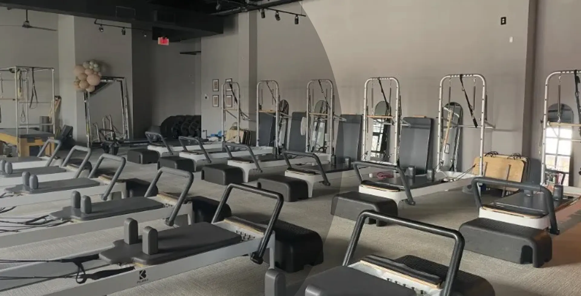 Spacious Reformer Pilates studio at BK Pilates Optimist Park with rows of modern Pilates reformer machines, black ceilings, and minimalist interior design