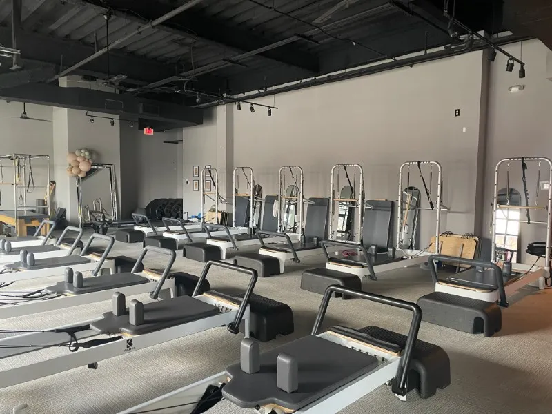 Spacious Reformer Pilates studio at BK Pilates Optimist Park with rows of modern Pilates reformer machines, black ceilings, and minimalist interior design