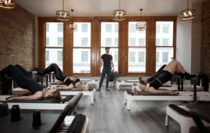 Instructor leading a group reformer Pilates class as part of a 5-day weekly workout plan in a NYC studio