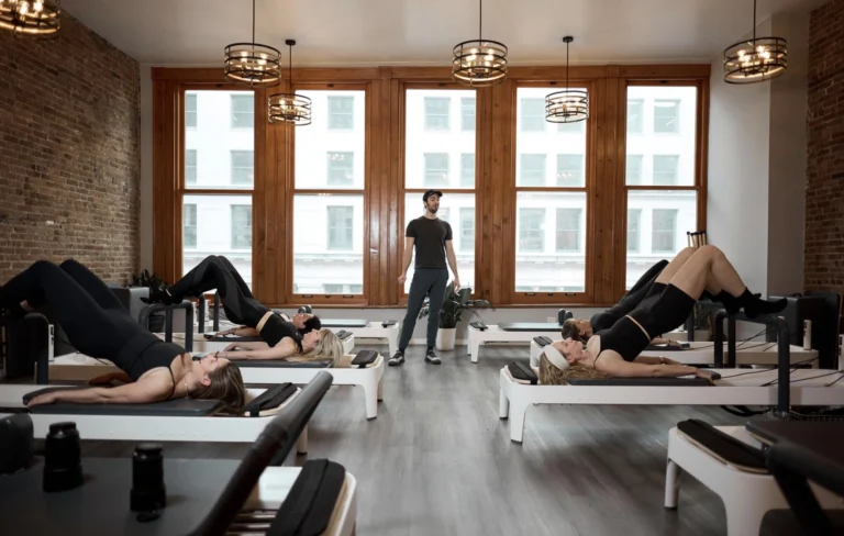 Instructor leading a group reformer Pilates class as part of a 5-day weekly workout plan in a NYC studio