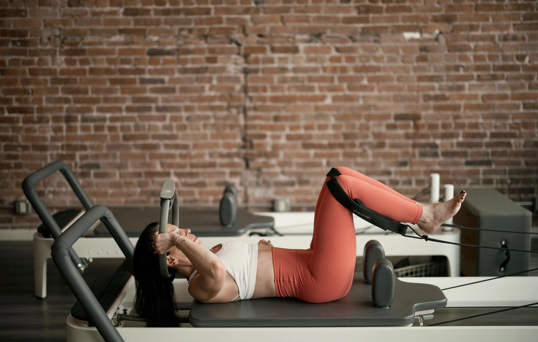 Woman engaging her obliques during a reformer Pilates exercise on the reformer carriage