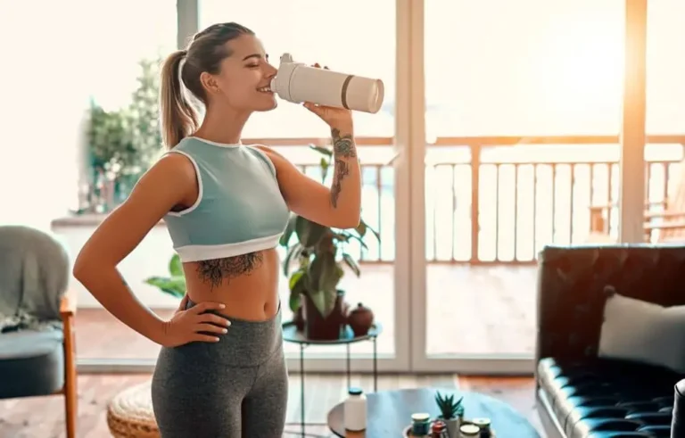 Woman drinking water at home before her reformer Pilates session
