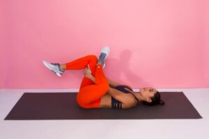 Woman doing a knee-to-chest stretch as part of an at-home stretching routine