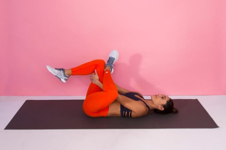 Woman doing a knee-to-chest stretch as part of an at-home stretching routine