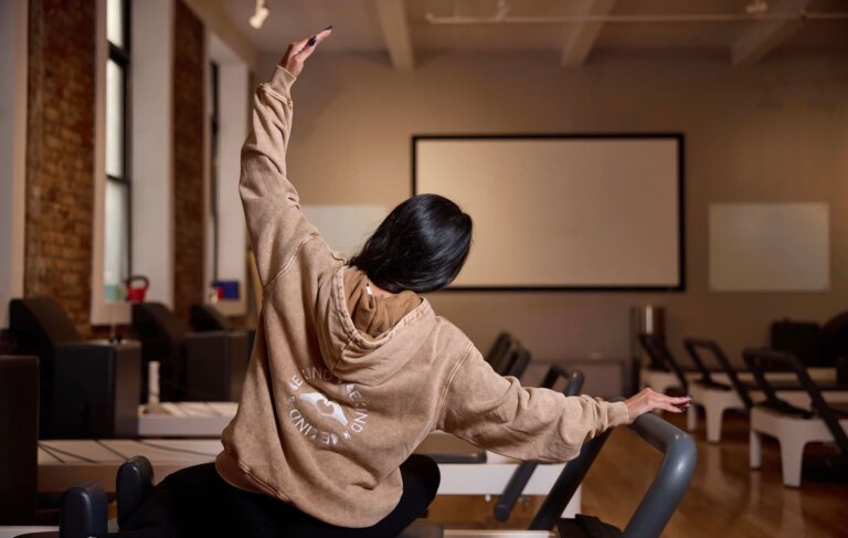 Woman doing a supported spinal rotation on the reformer, part of Pilates exercises used for back pain relief