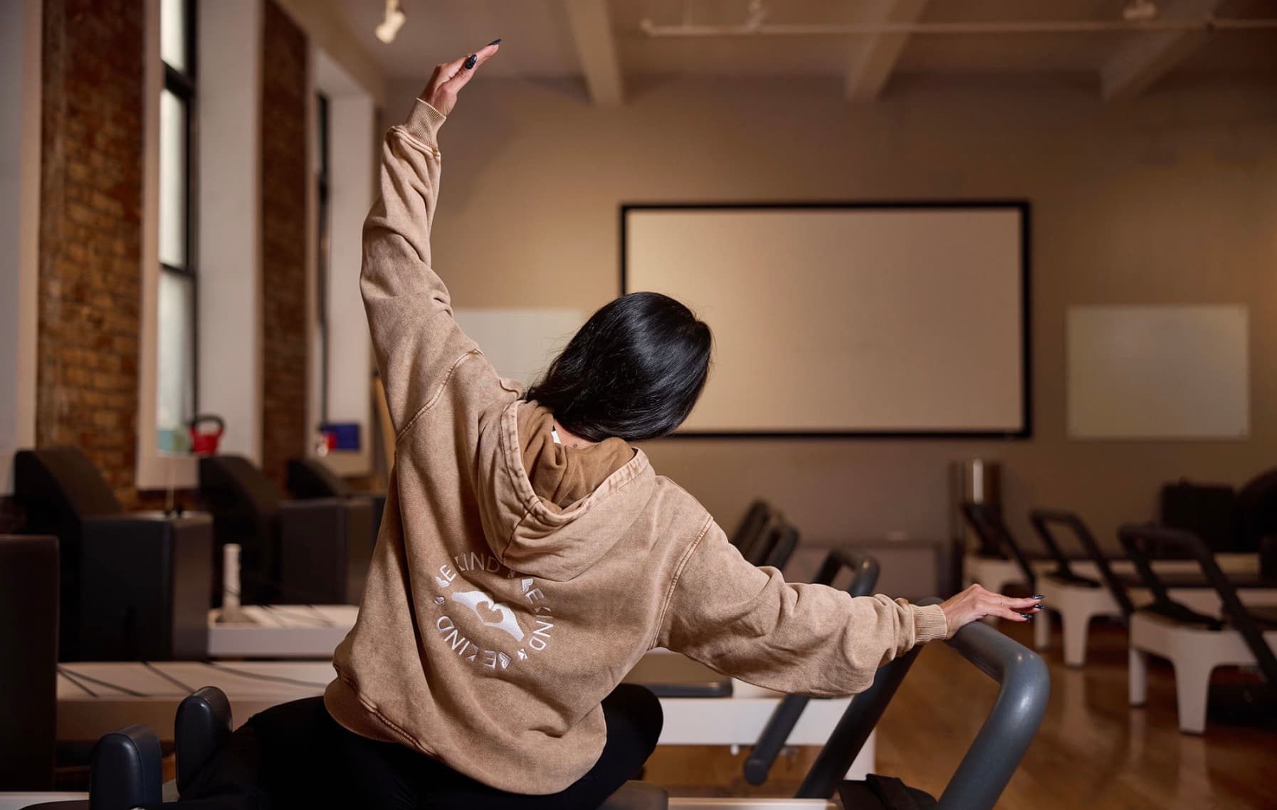 Woman doing a supported spinal rotation on the reformer, part of Pilates exercises used for back pain relief