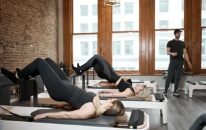 Instructor guiding a group pilates reformer class focused on core strength exercises