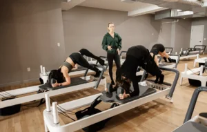 Instructor guiding a small reformer Pilates class through a supported core exercise at BK Pilates